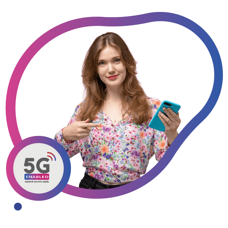 Young woman holding a blue smartphone and pointing at it, promoting 5G enabled mobile network.